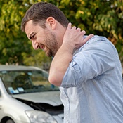 Man rubbing back of neck after car accident