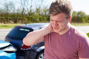 Man rubbing neck after car accident