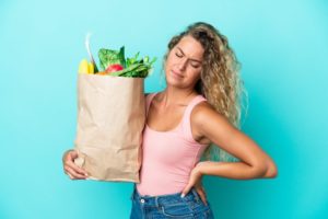 woman holding groceries with back pain