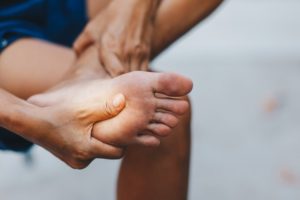 hand holding foot in pain