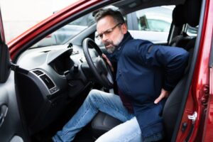 man in his car with lower back pain
