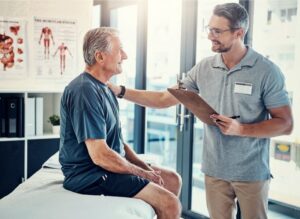 chiropractor setting a hand on the smiling patient’s shoulder